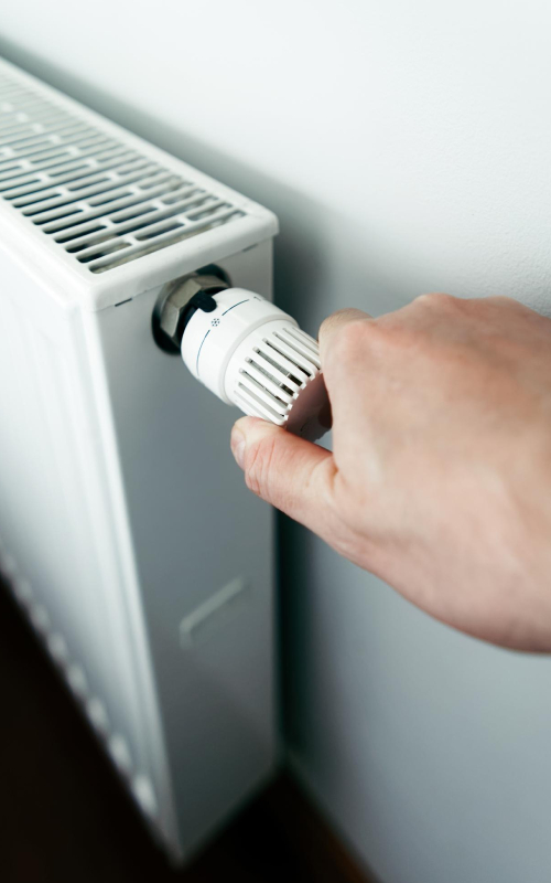Réglage de radiateur pour installation de chauffage Main réglant le thermostat d’un radiateur dans le cadre d’une installation de chauffage